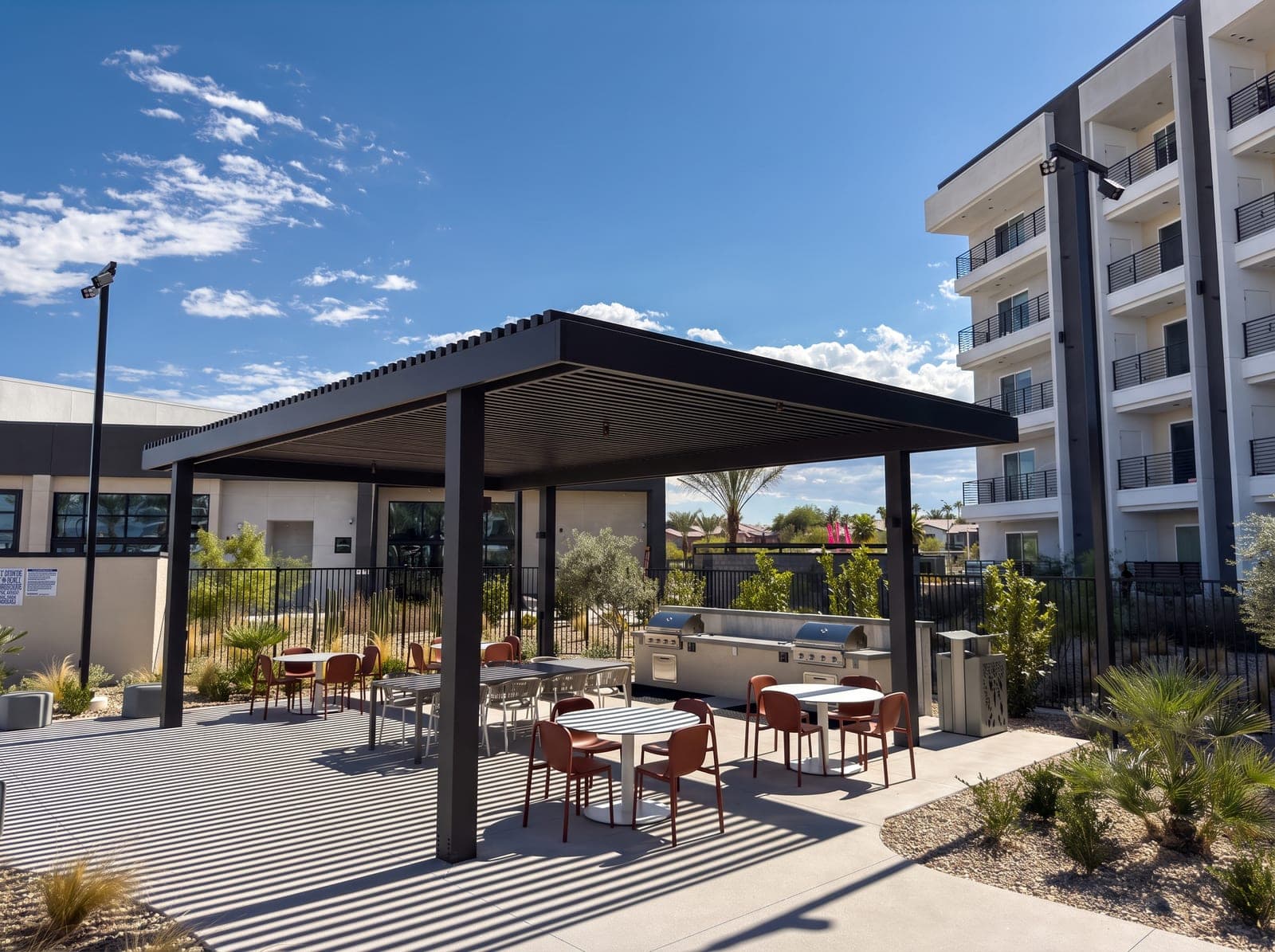 Espresso lattice-top pavilion over grills and dining tables beside an apartment building at ARCA Apartments