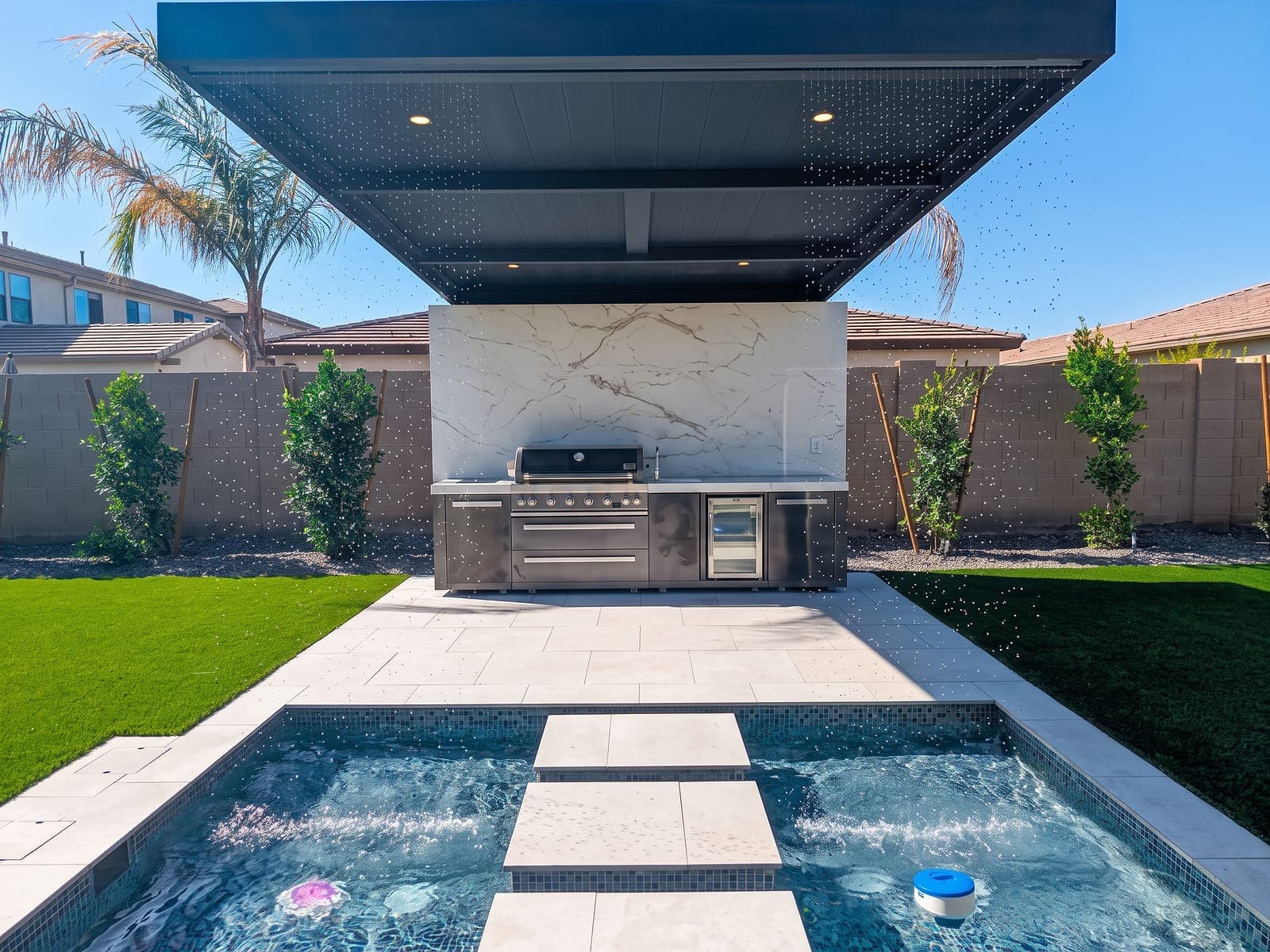 Black cantilever with a Twin Wall roof over an outdoor kitchen beside a pool