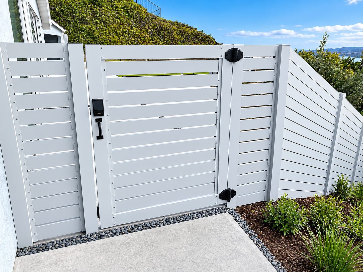 Horizontal aluminum slat fence and pedestrian gate with a keypad lock along a side yard.