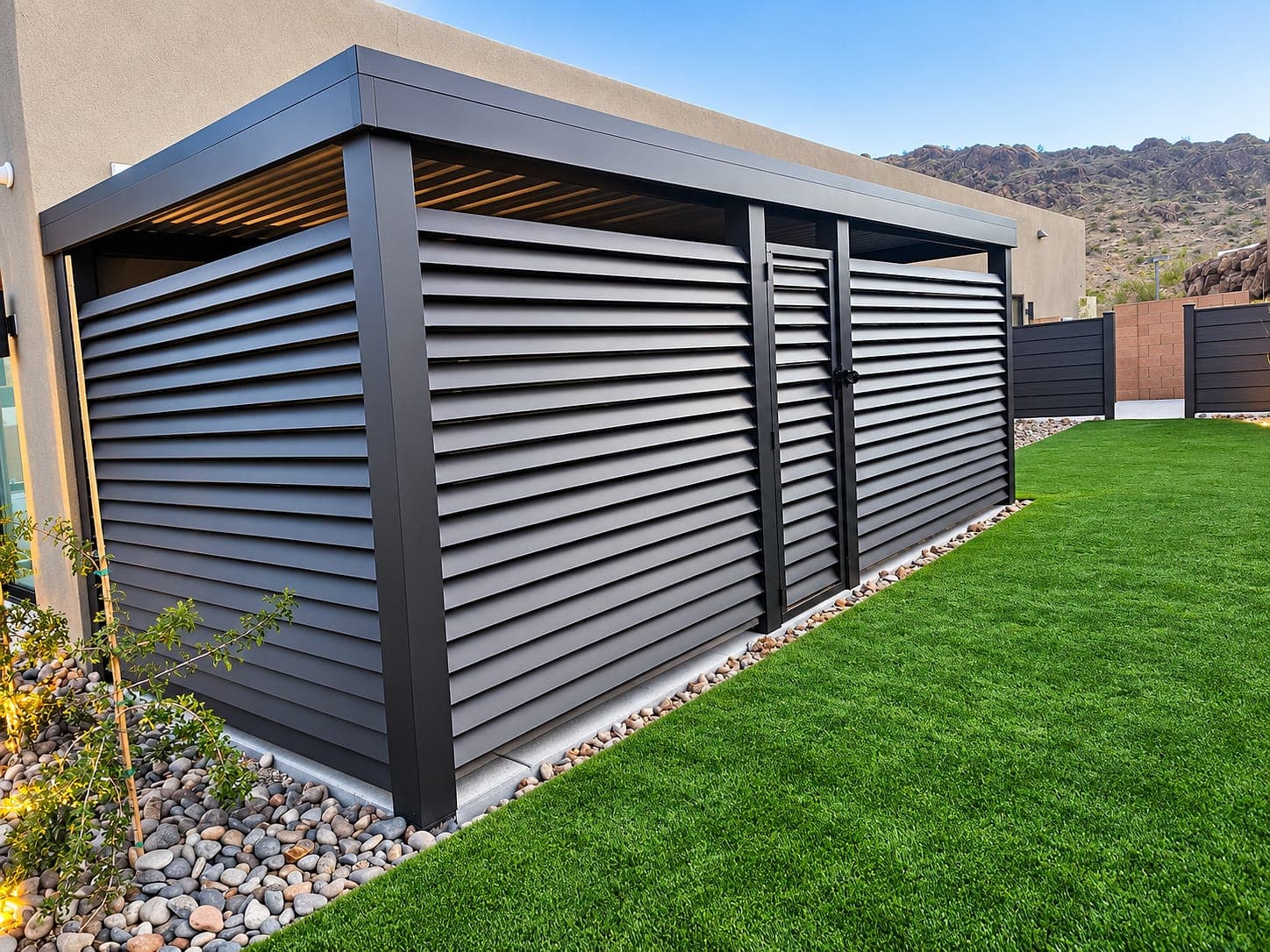 Aluminum fence of fixed, angled 1″ × 4″ lattice boards with a pedestrian gate along the side of a home, beside a lawn.