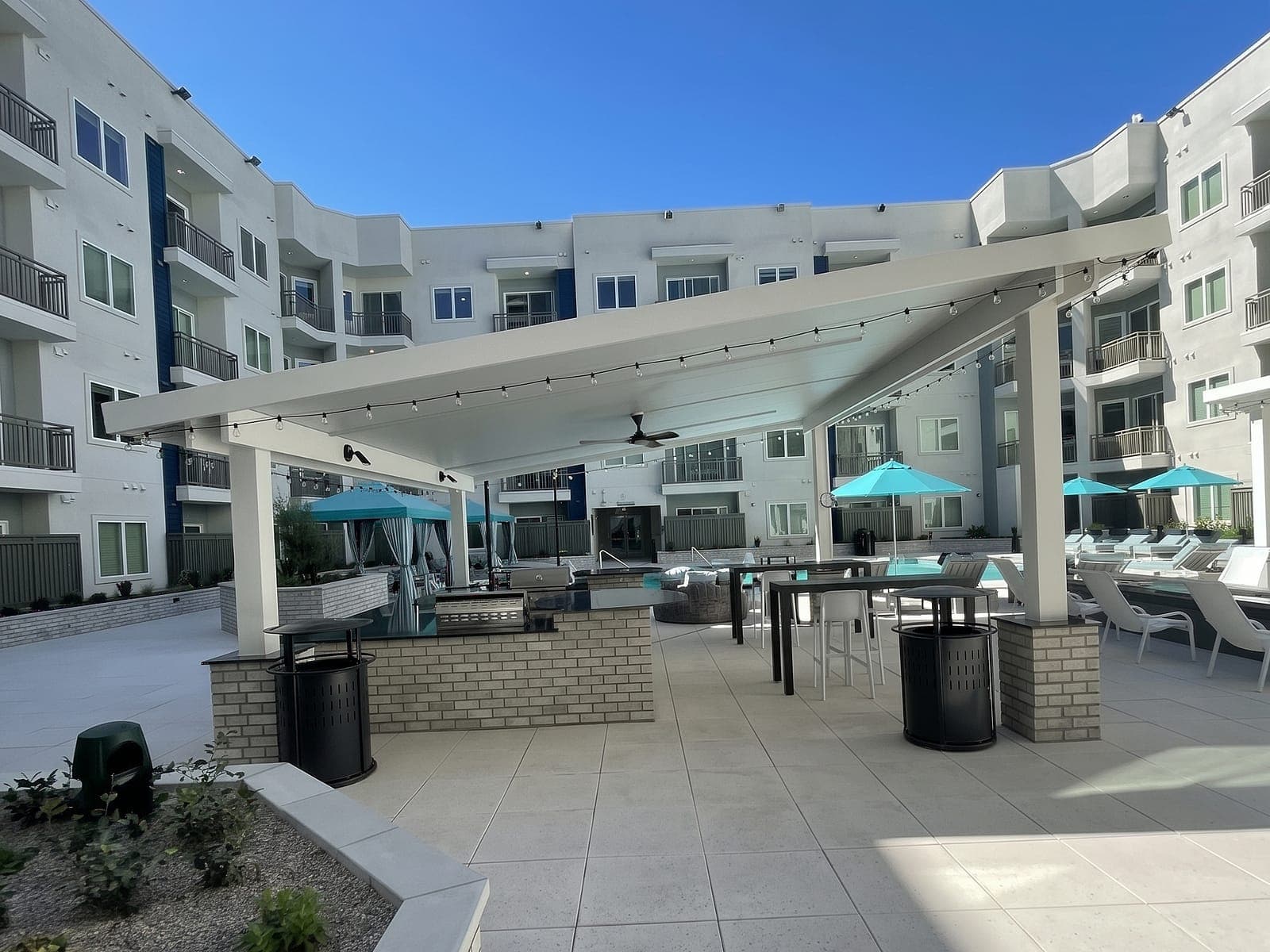 Freestanding pergola with a white VEER roof over an outdoor kitchen in an apartment courtyard