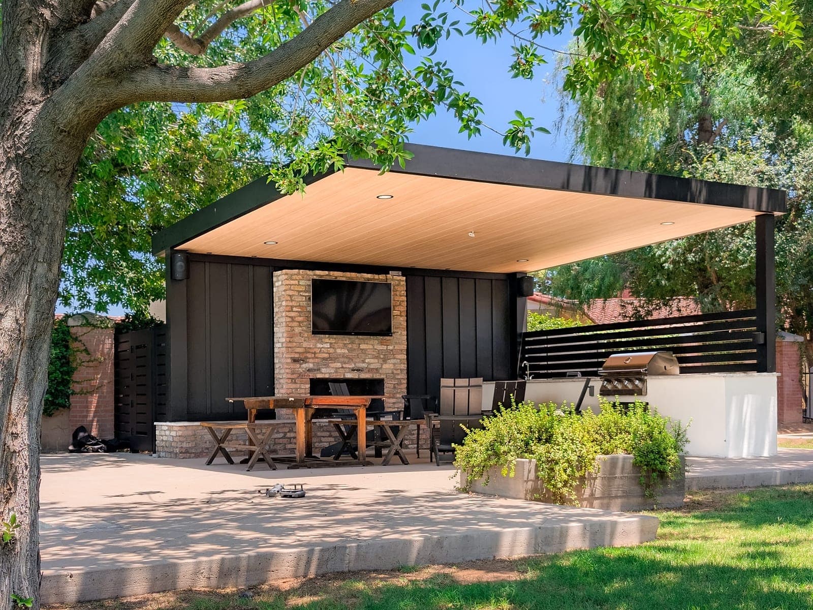 Three-post patio cover with a Sandalwood VEER roof over a backyard dining area