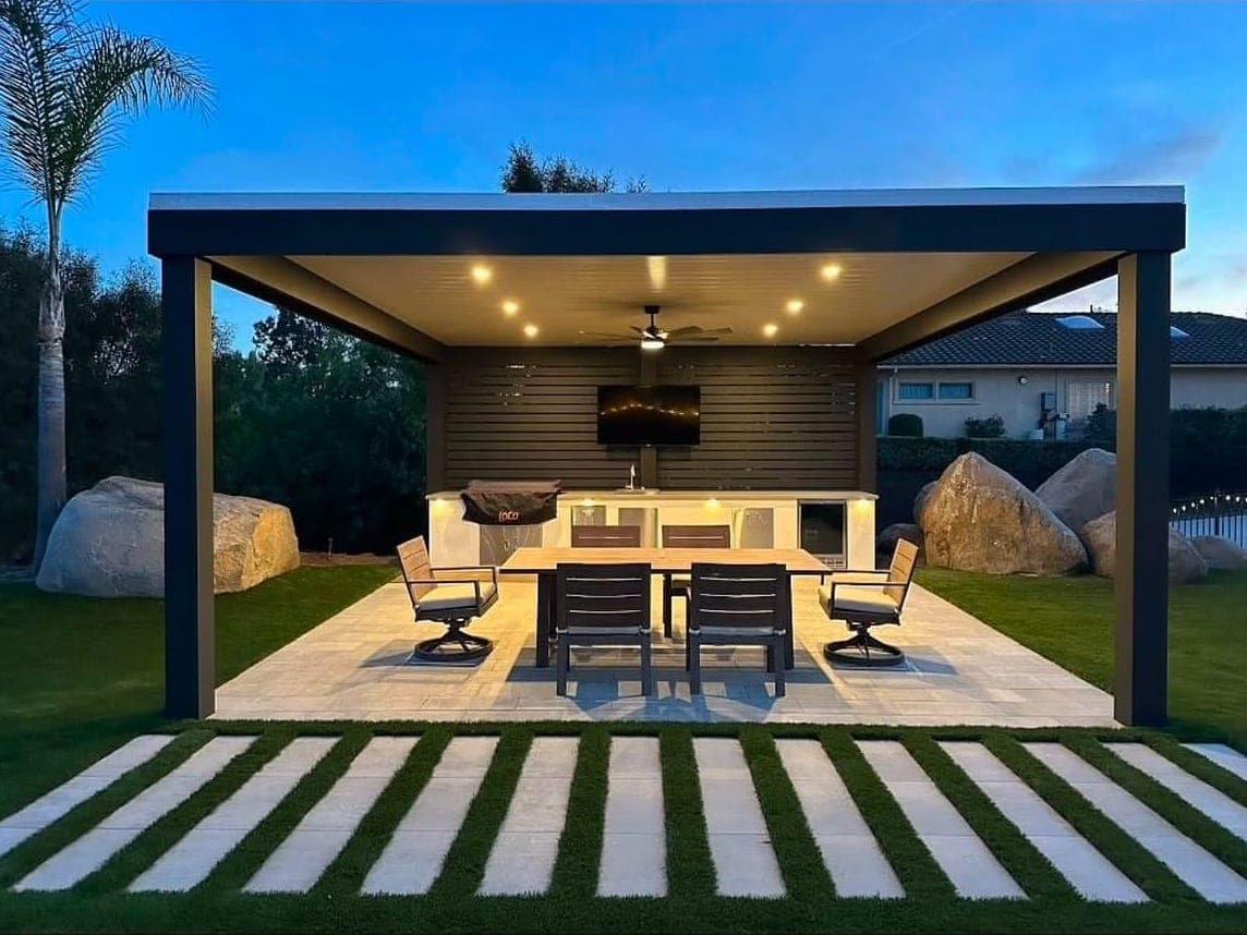 Freestanding cover with white VEER panels over an outdoor dining area at dusk