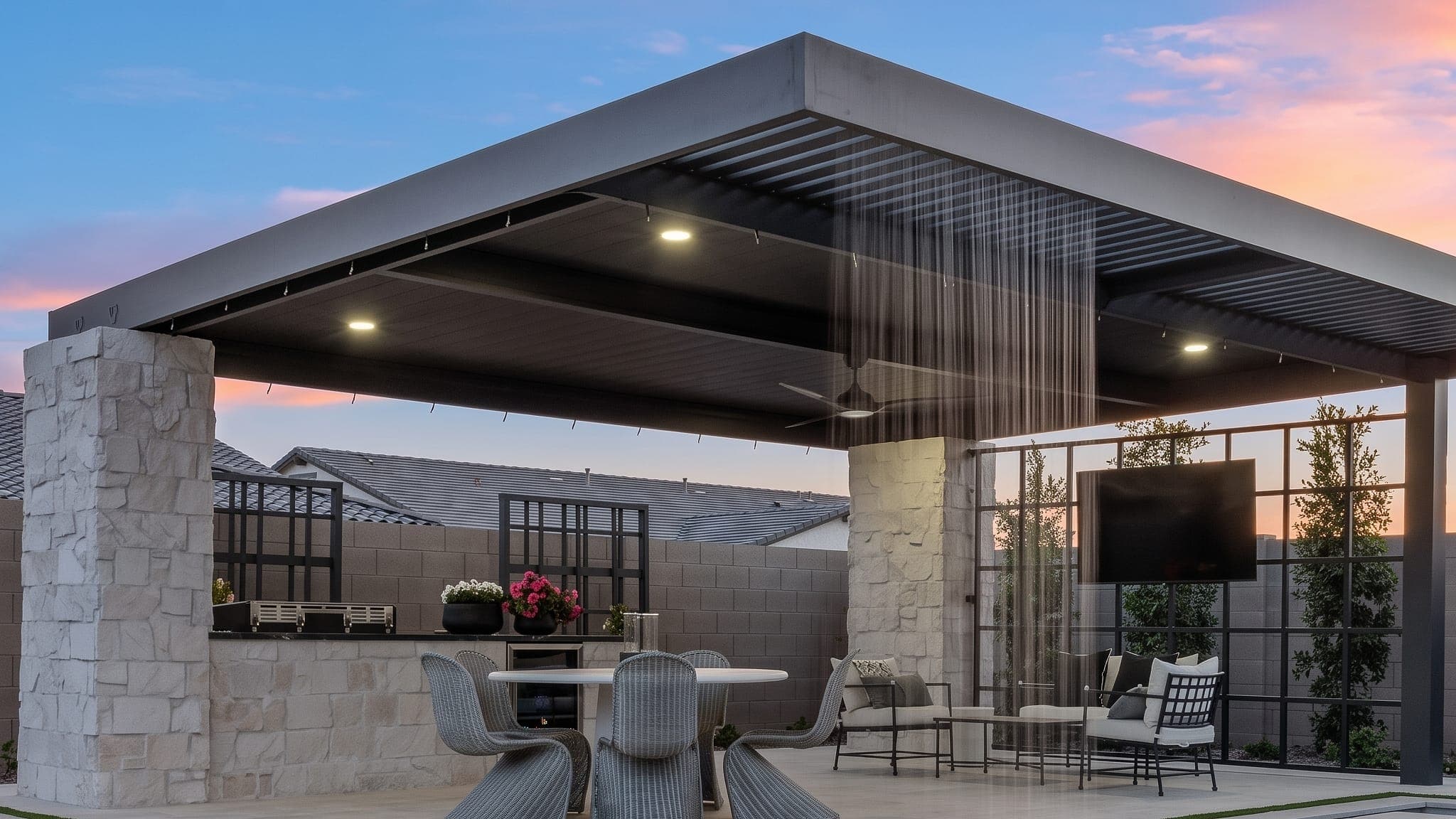 Combo lattice and VEER panel pergola with a rain curtain beside a pool at dusk